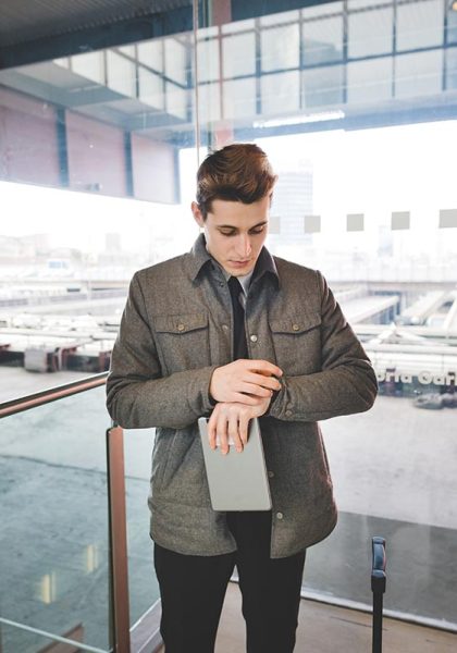 Portrait of young businessman commuter checking wristwatch for time.